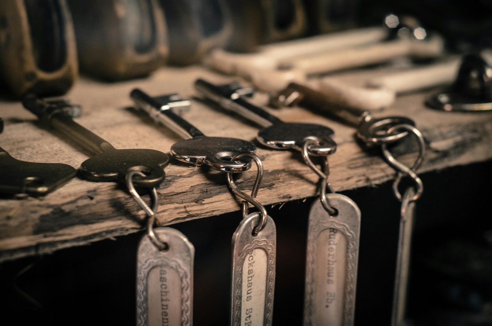 A detailed shot of antique metal keys with keychains hanging on a rustic wooden surface.