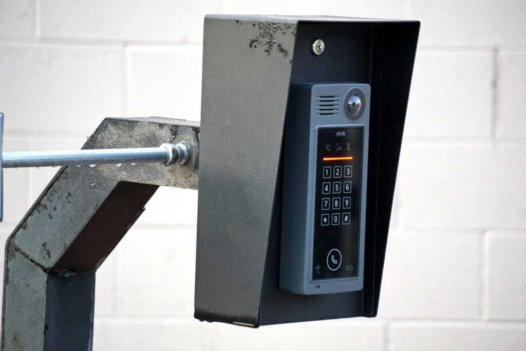 Close-up of a modern security intercom and keypad mounted on a wall outdoors with visible wiring.