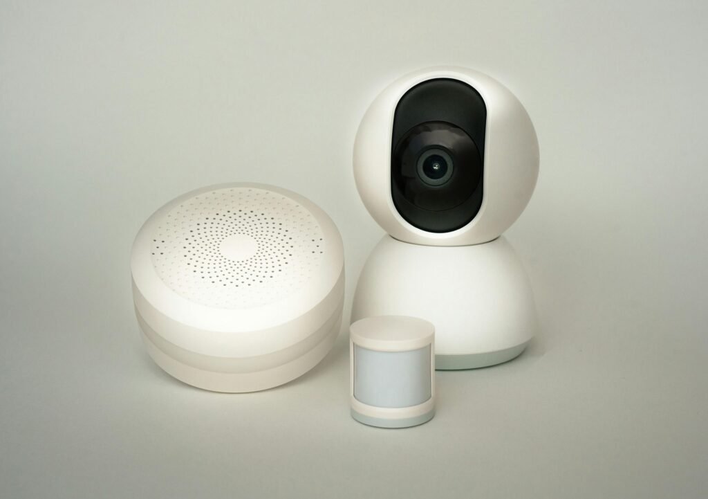 Modern smart home devices including a camera and sensors on a neutral background.
