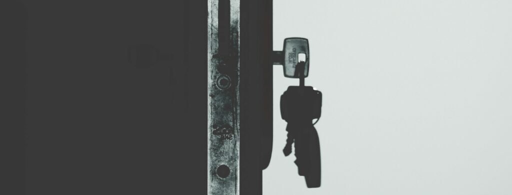 Serrure bloquée : Le guide d'expertise pour diagnostiquer, réparer et sécuriser Black and white image showcasing a door lock with a key inserted, casting shadows.